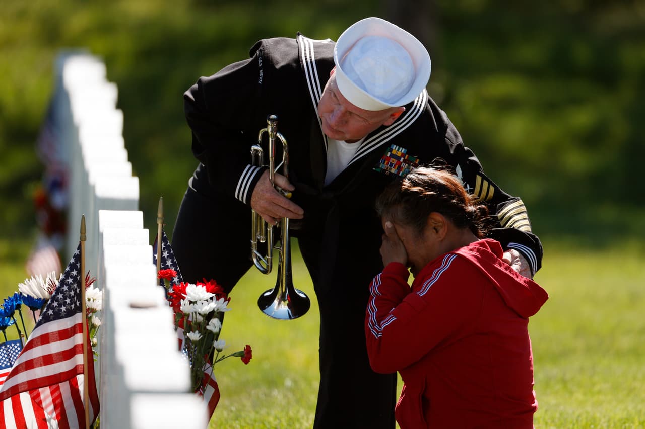 El jubilado de la Armada de los EEUU, Mark Stallins, consuela a una mujer que llora ante la tumba de su pariente en el cementerio nacional de Fort Logan en Sheridan, Colorado.