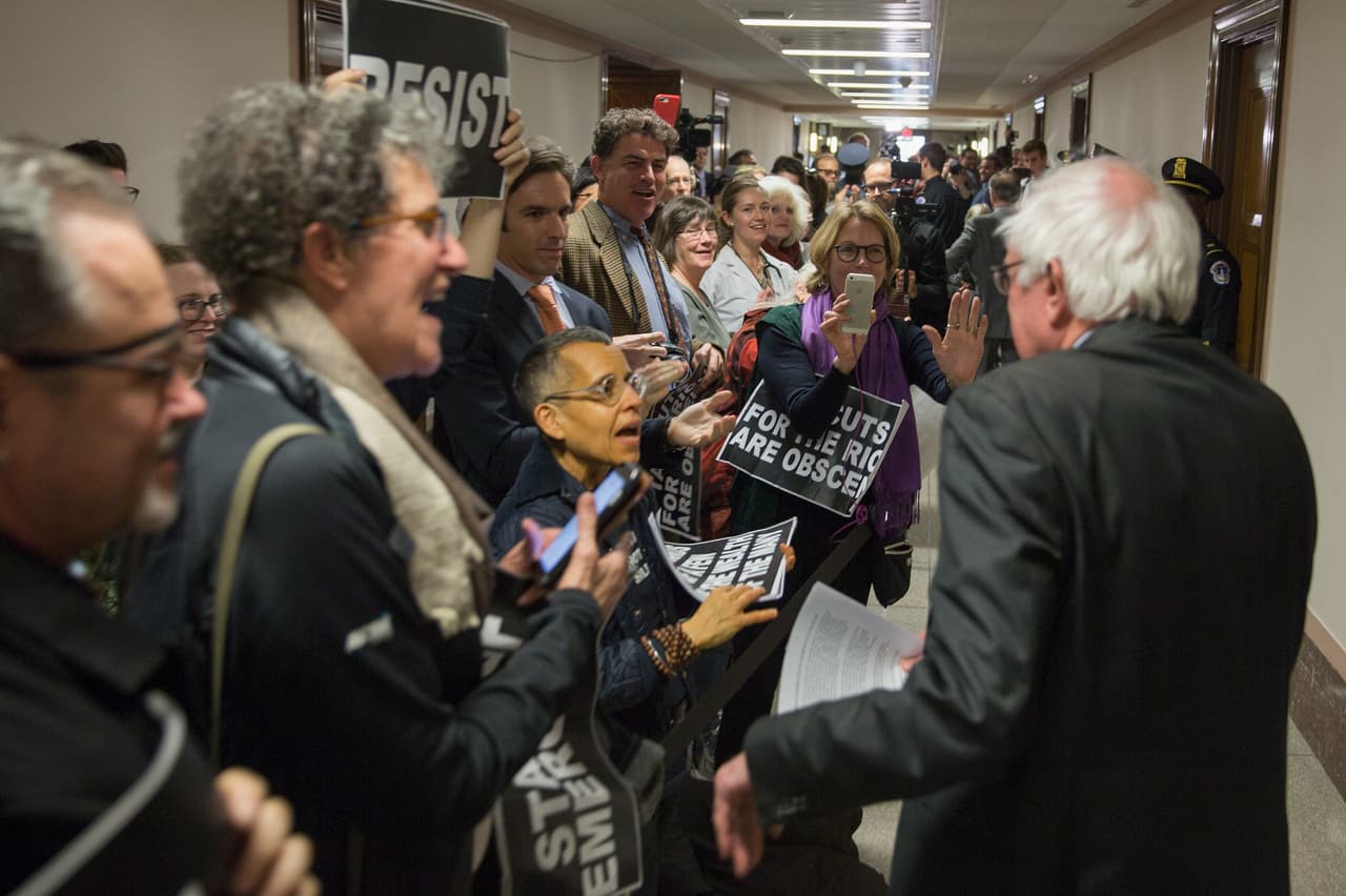 Los manifestantes saludaron al senador Bernie Sanders, opositor al proyecto de ley, en su camino a la sala de audiencias. Los republicanos en el Senado esperan aprobar la legislación esta semana, trabajar con la Cámara de Representantes y tener una ley firmada por el presidente antes de Navidad.