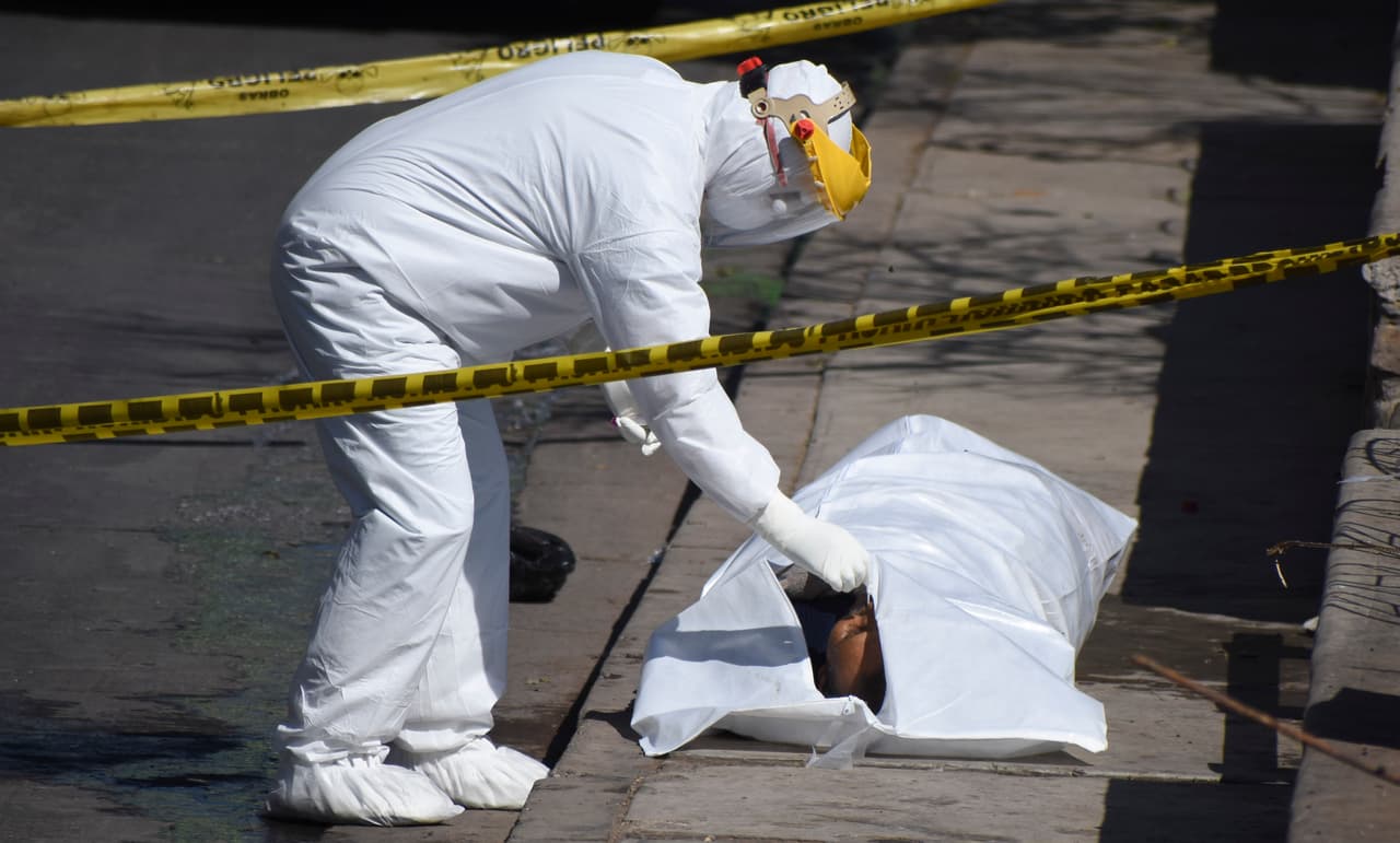 Un trabajador de los servicios de salud en Cochabamba, Bolivia, recoge una muestra nasal de un cuerpo dejado en una acera, aparentemente víctima del nuevo coronavirus.