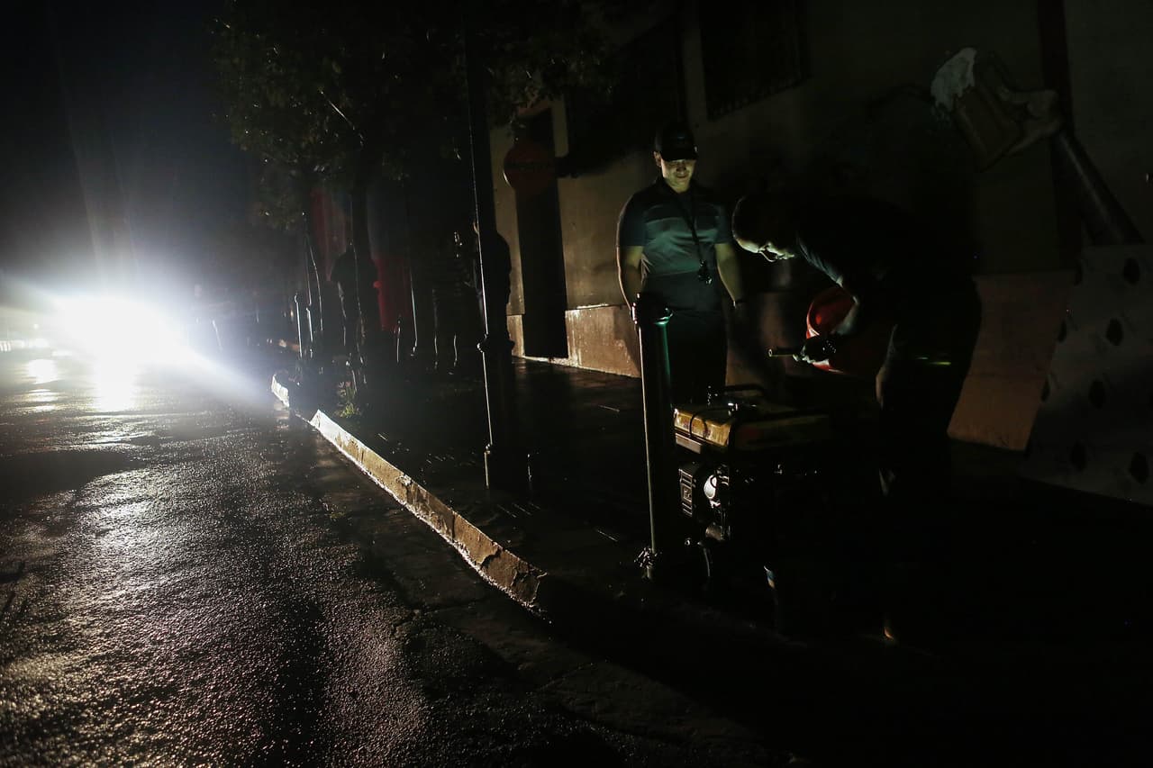 <b>Electricidad: 18.5%.</b> El sistema eléctrico de la isla colapsó casi en su totalidad. Casi todas las vías de Puerto Rico están rodeadas de postes caídos y cables en el suelo. En la imagen, un hombre llena de gasolina un generador en la oscuridad en una calle de Albonito, en la región central el 11 de octubre de 2017.