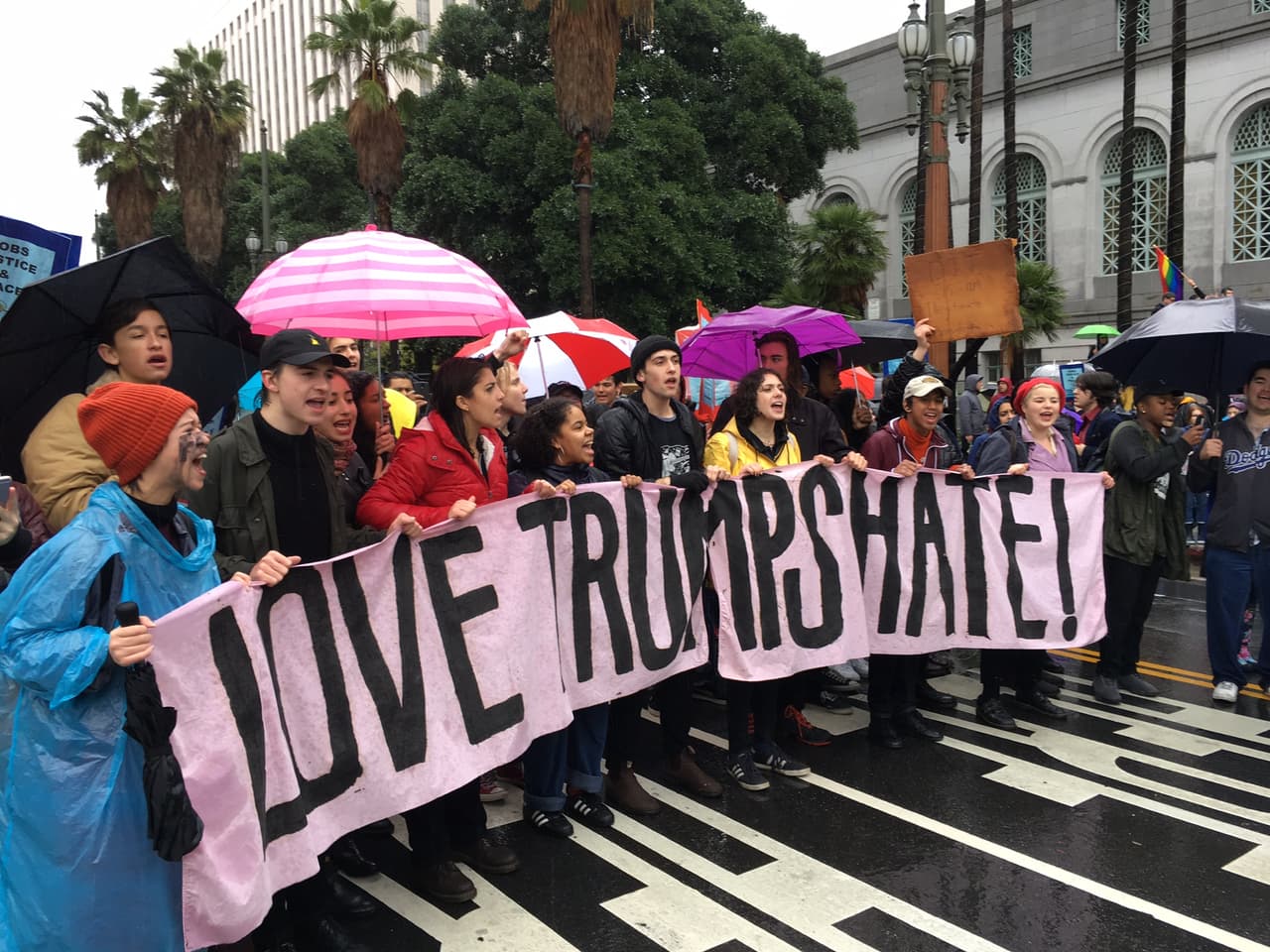 Un grupo de jóvenes de distintas etnias sostiene una manta con el lema: ‘Ama el odio de Trump’.