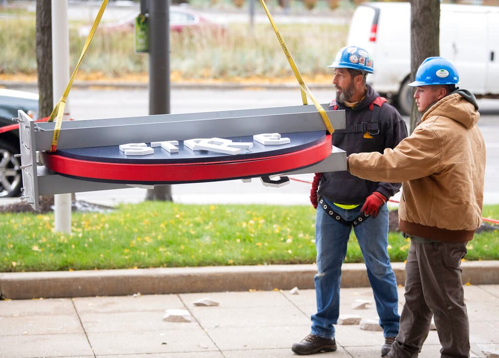 Un trabajador de la empresa Brilliant Electric Sign Company sostiene un fragmento roto del letrero