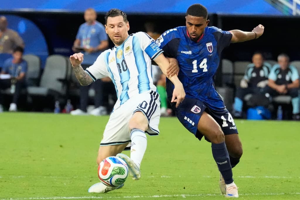 Lionel Messi y Deroy Duarte pelean el balón en medio campo.