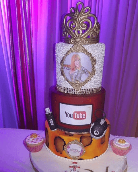 Este es uno de los pasteles que endulzaron el festejo de Bustos. Cuatro pisos con diversos decorados, como su fotografía, una corona y el logotipo de 
<b><a href="https://www.youtube.com/channel/UCGFfsGEhZIzMrLeC9M3F_lA" target="_blank">YouTube</a></b>, plataforma donde la famosa peruana se dio a conocer.