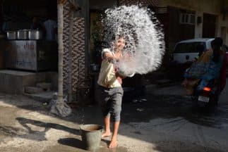 Un trabajador en India lanza agua sobre el pavimento, afuera de un restaurante, en un intento de mantener la calle fresca. 