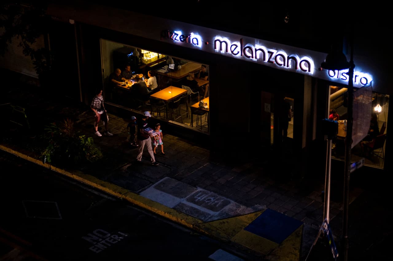 La gente camina frente a un restaurante que funciona con un generador en San Juan, Puerto Rico.