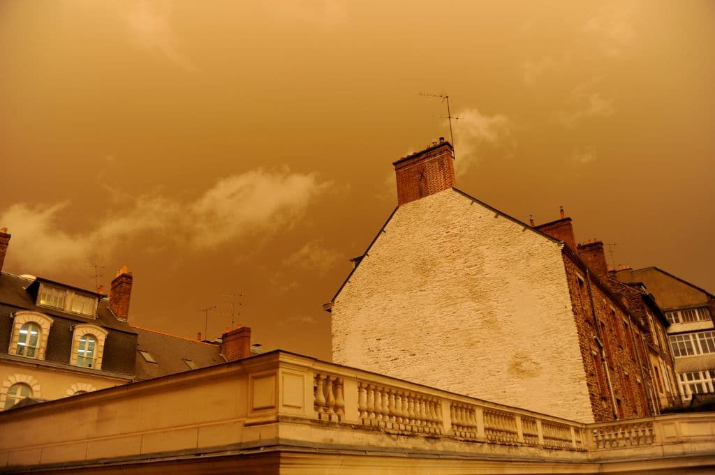 A picture taken on October 16, 2017, in central Rennes, western France, shows rooftops and the sky after it turned a yellow-ochre colour due to sand from the Sahara desert and dust from wildfires in Portugal being carried by wind from the Storm Ophelia. / AFP PHOTO / Marie DUFAY (Photo credit should read MARIE DUFAY/AFP/Getty Images)