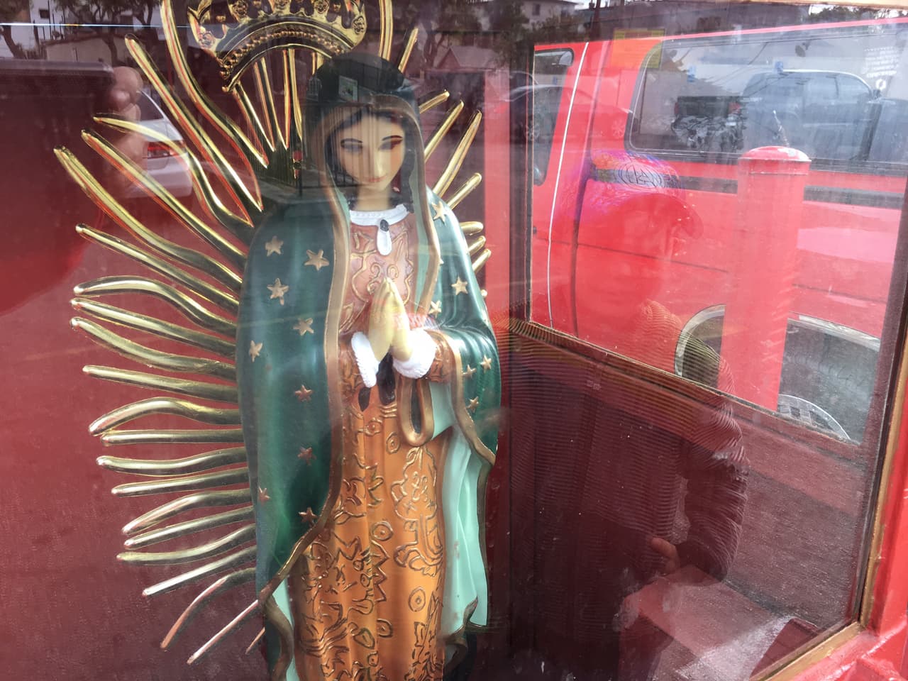Afuera de una plaza angelina, dos niños observan la estatua de una Virgen.