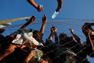 Un hombre macedonio vende agua a refugiados y migrantes en un campo de acogida tras cruzar la frontera con Grecia