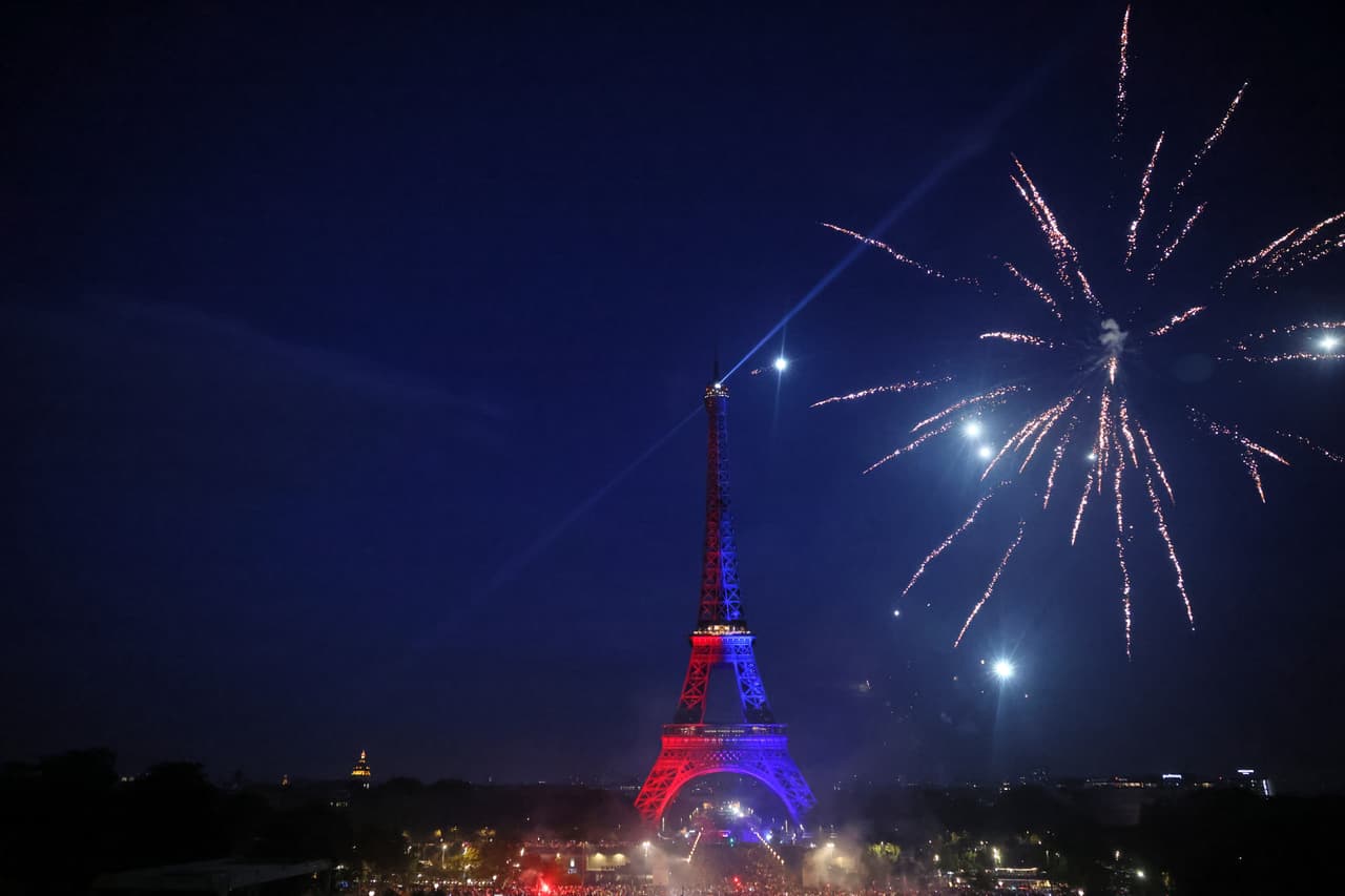 Fuegos artificiales estallan junto a la Torre Eiffel mientras los hinchas del PSG celebran en París.
