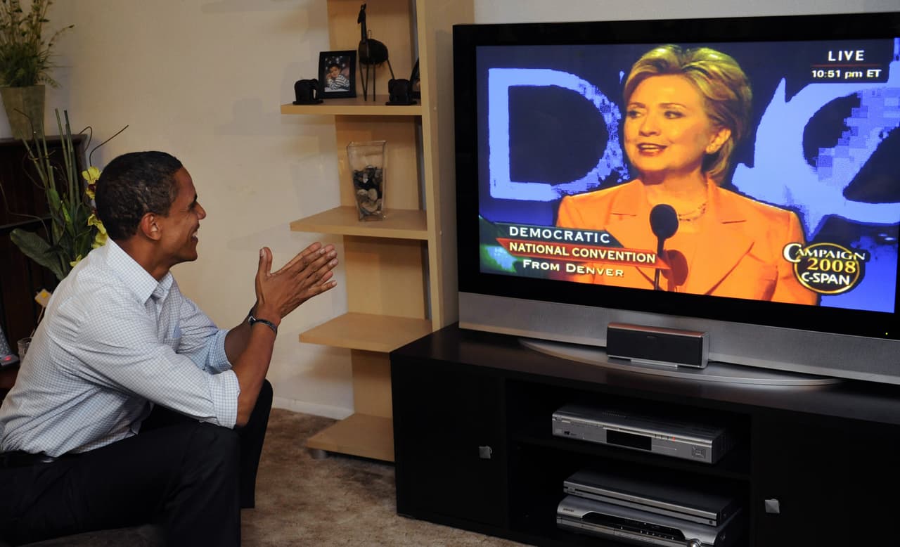 Obama observa por televisión a Hillary Clinton mientras ella se dirige a un grupo de seguidores en Billings, Montana, durante la Convención Nacional Demócrata, el 26 de agosto de 2008. Foto por EMMANUEL DUNAND/AFP/Getty Images.