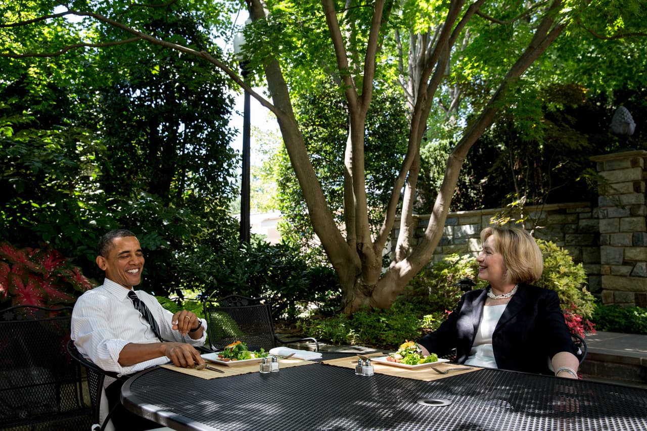 En esta foto proveída por la Casa Blanca, el presidente Obama almuerza con Clinton después de que ella saliera de su cargo como secretaria de Estado en el patio de la Oficina Oval, el 29 de julio de 2013, en Washington, DC. El último día de Clinton como secretaria de Estado fue el 1 de febrero de 2013. Foto por Chuck Kennedy/White House via Getty Images.