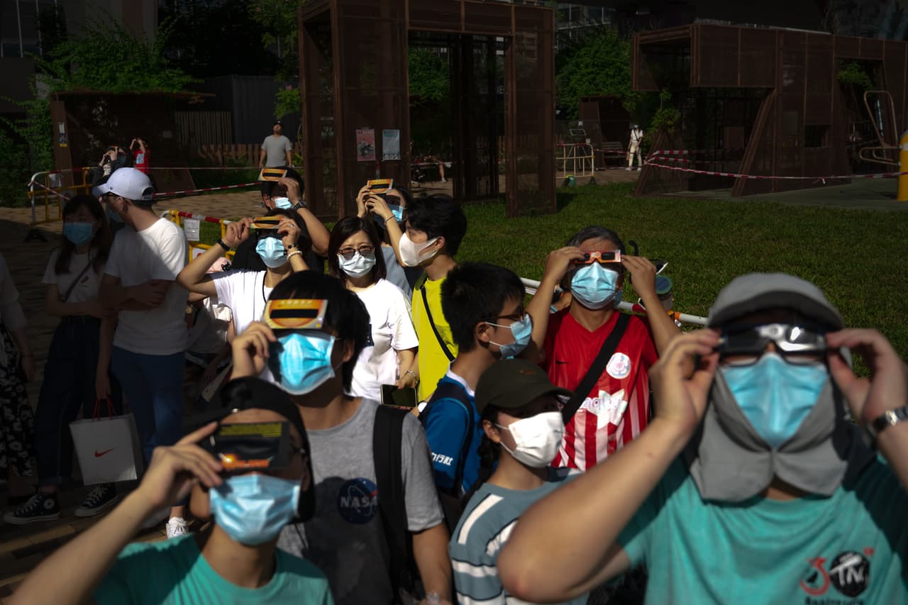 Gente en Pekín, China, con mascarillas protectoras, contemplando el 'Anillo de fuego', un fenómeno que no se podrá ver nuevamente sino hasta dentro de 14 años, según astrónomos.