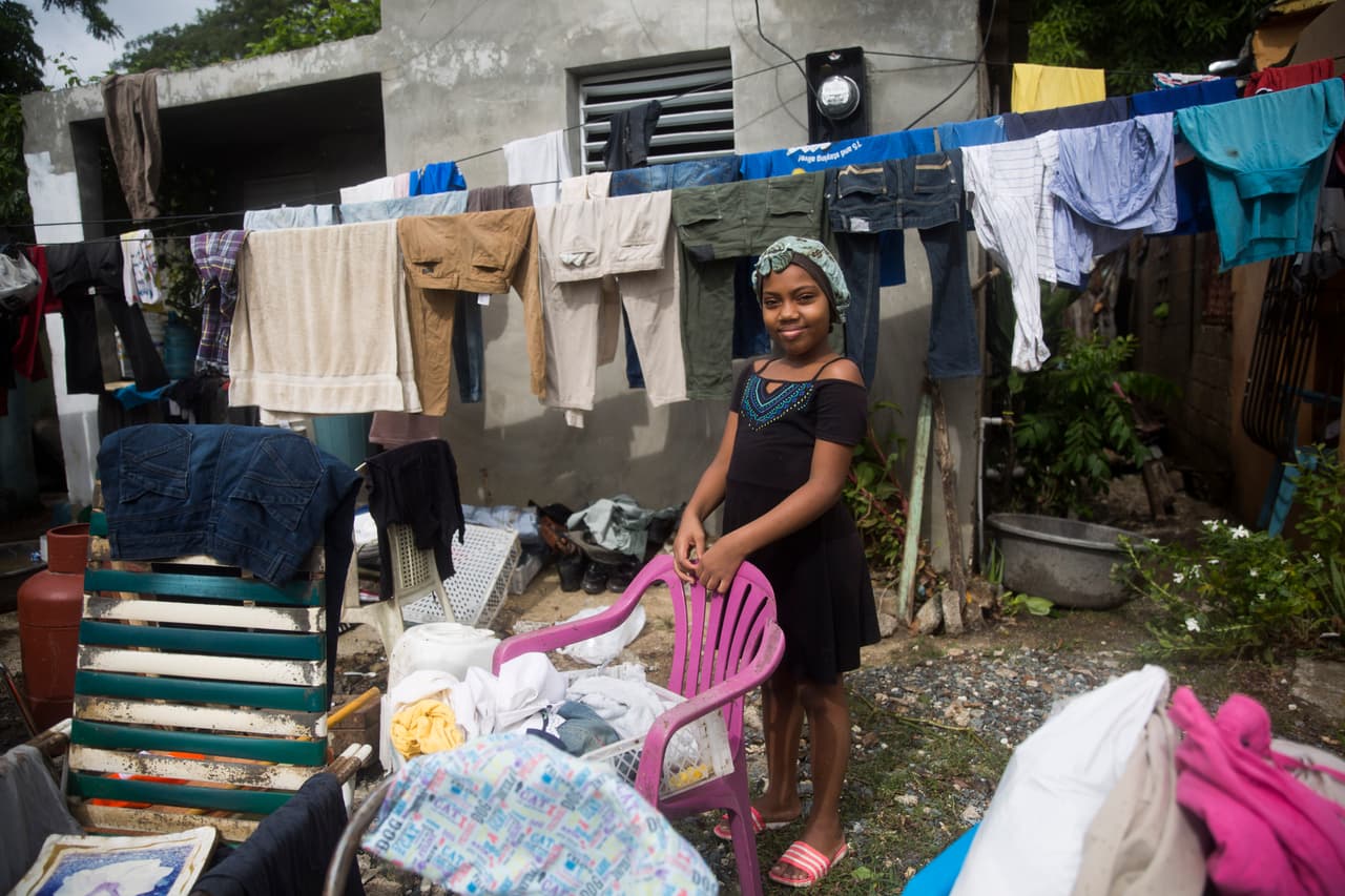 Una chica está de pie junto a las pertenencias de su familia en la ciudad de Hato Mayor.