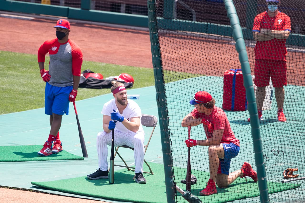 Los jugadores se reunieron en el campo. Algunos usaron cubrebocas y otros no. En esta foto, Jean mira como Bryce Harper y Rhys Hoskins reaccionan durante los entrenamientos.
