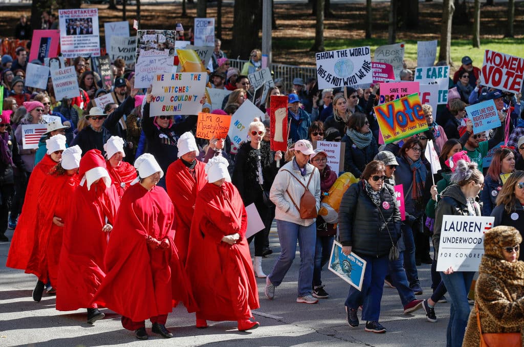 El vestido rojo que todas estas manifestantes, madres, estudiantes, profesionales, reivindicadoras de los derechos han adoptado en los últimos años para sus protestas pacíficas es, en realidad, una especie de disfraz, uno que recrea con exactitud el vestuario que usan las mujeres de la serie de Hulu ‘El cuento de la criada’ (su título original en inglés es 
<a href="https://www.hulu.com/series/the-handmaids-tale-565d8976-9d26-4e63-866c-40f8a137ce5f">'The Handmaid's Tale')</a>, inspirada 
<a href="https://www.amazon.com/s/?ie=UTF8&keywords=the+handmaid%27s+tale+book&tag=googhydr-20&index=aps&hvadid=241642082557&hvpos=1t2&hvnetw=g&hvrand=17040019017323962023&hvpone=&hvptwo=&hvqmt=e&hvdev=c&hvdvcmdl=&hvlocint=&hvlocphy=9051839&hvtargid=aud-509611686427:kwd-13599567661&ref=pd_sl_8eet4uh72x_e">en la novela del mismo nombre</a> escrita en 1984 y publicada un año después por Margaret Atwood.