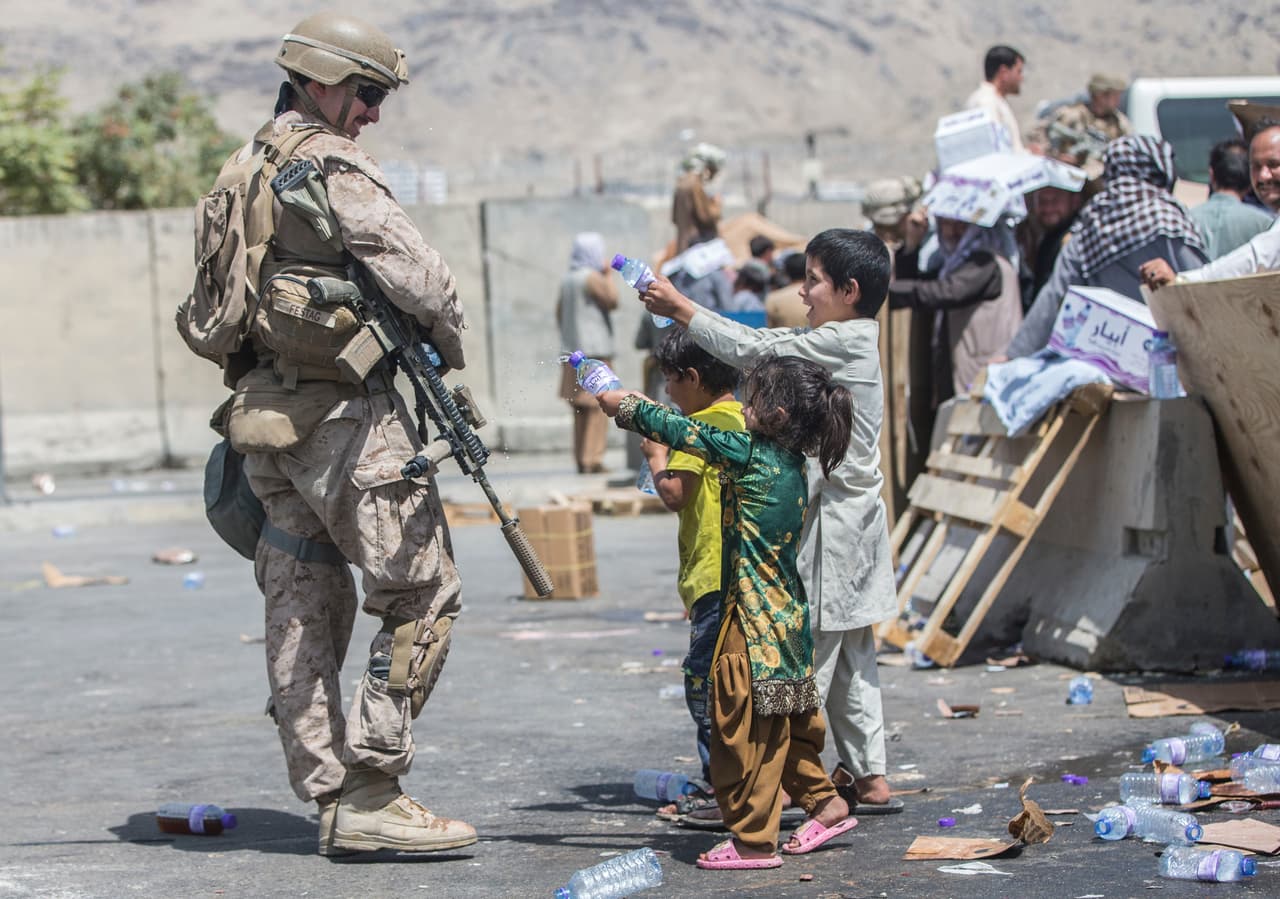 Niños afganos lanzando agua a un soldado estadounidense, el 21 de agosto, en el aeropuerto de Kabul. Solo 42% de los pequeños nacidos en Afganistán son registrados legalmente,
<a href="https://www.unicef.org/rosa/media/10551/file/Afghanistan.pdf"><u>según datos de UNICEF de 2015</u></a>.