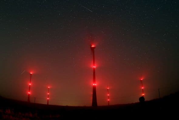 Una Perseida cruza el cielo de Gemuend, al oeste de Alemania, mientras los iluminados molinos de viento están a la expectativa.