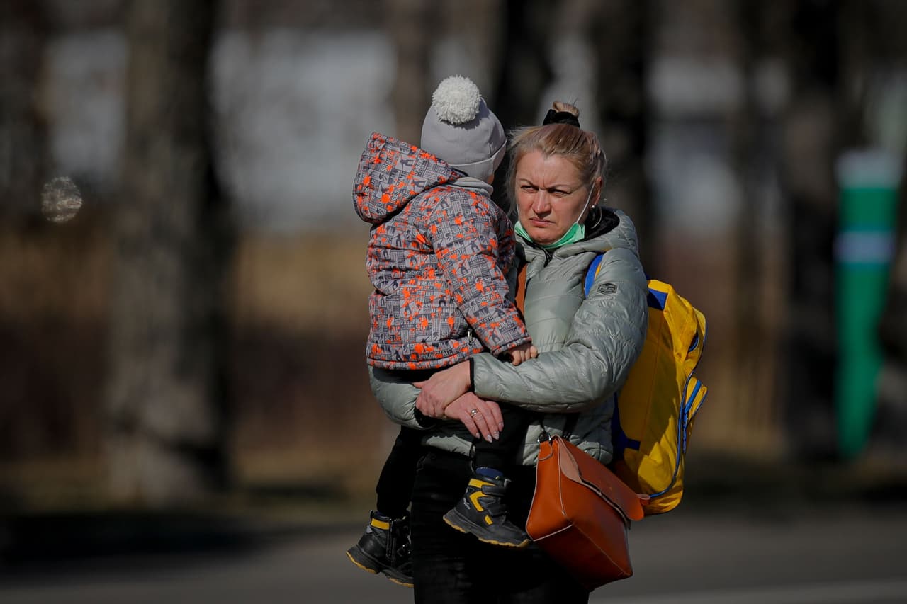 De la suspensión de las medidas de restricción de viajes por el covid-19 también se beneficiarán aquellos desplazados ucranianos que ingresen en Rumanía a través de la vecina república de Moldavia. En la fotografía una mujer ucraniana sostiene a un niño después de cruzar la frontera hacía Rumania en la ciudad de Siret.
<br>