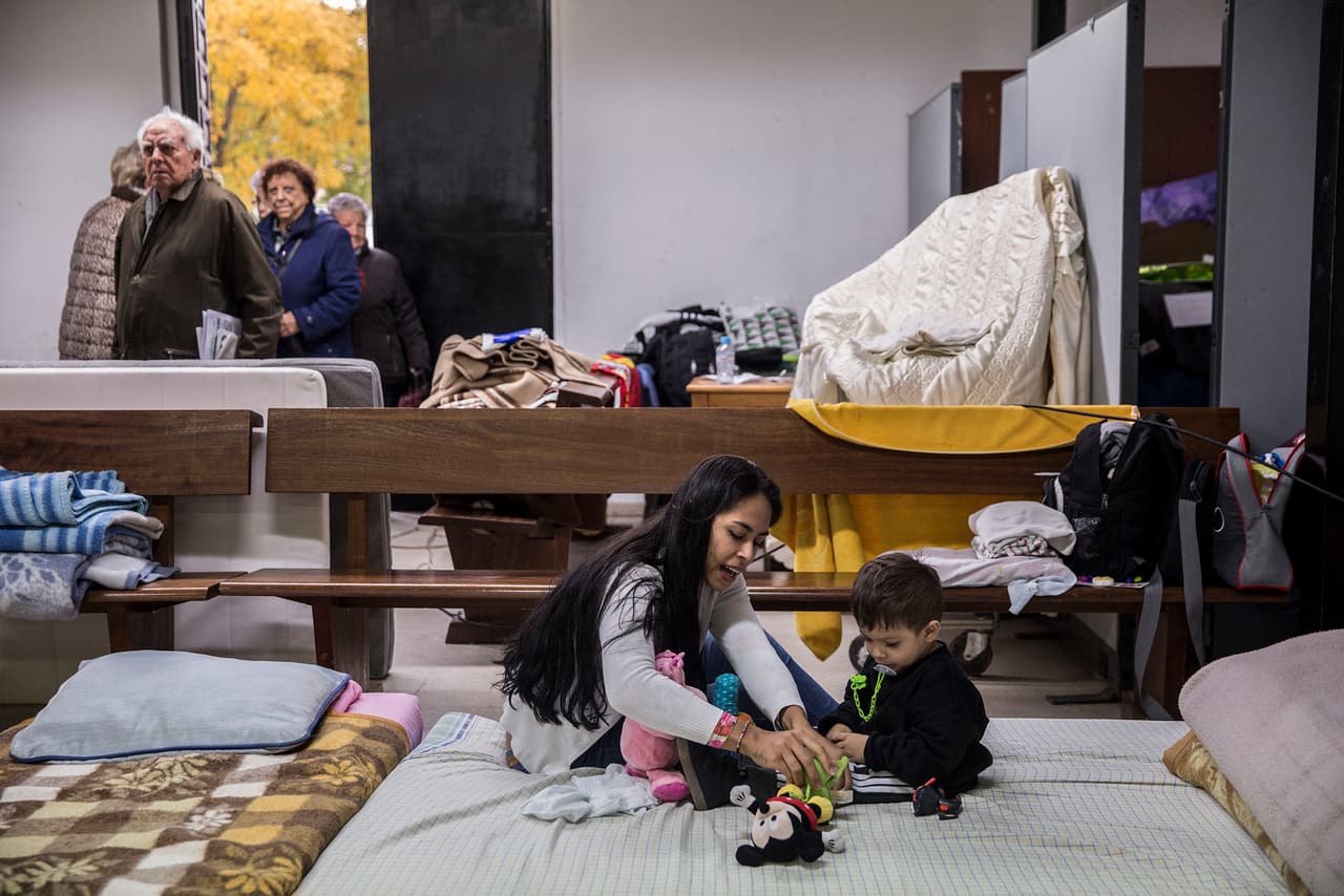 Sandra, a young Colombian mother, and her son Mattias, play inside the San Carlos Borromeo parish chuch while neighbors of the Vallecas neighborhood visit asylum-seeking families.