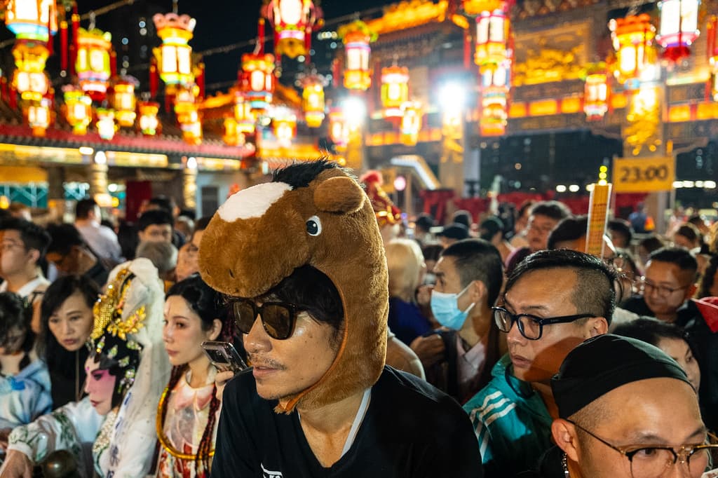 Este hombre lleva un gorro de un Caballo en la celebración del Templo Wong Tai Sin, en Hong Kong, entre personas con disfraces y máscaras y miles de farolillos.
