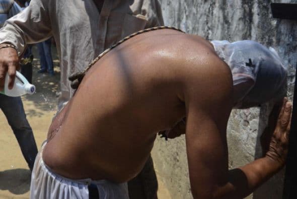 Un hombre vierte alcohol en el coxis de un devoto en Santo Tomás, departamento Atlántico, Colombia.