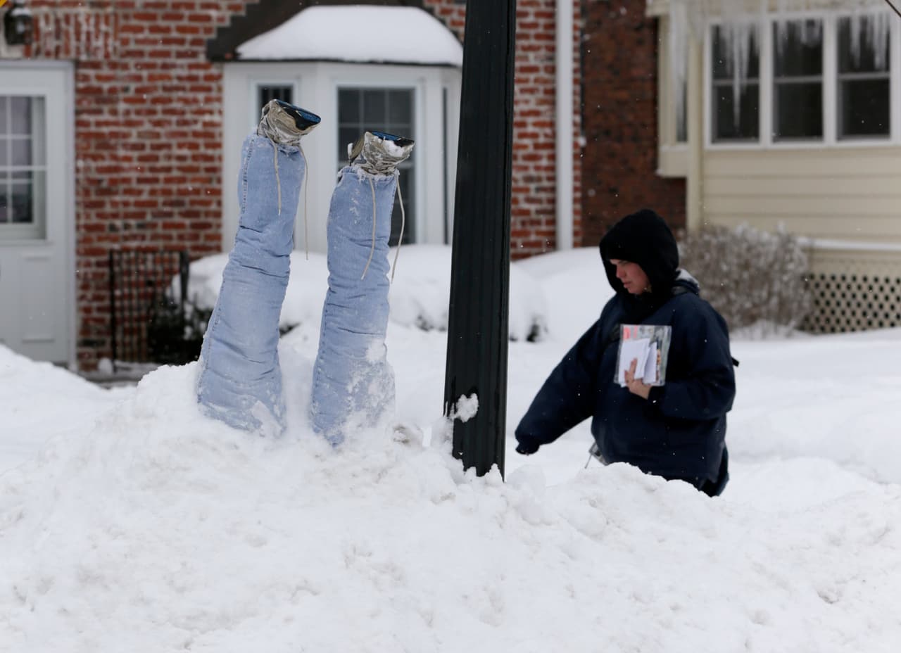Un repartidor del servicio de correos camina por una de las calles repretas de nieve de Omaha, en Nebraska.