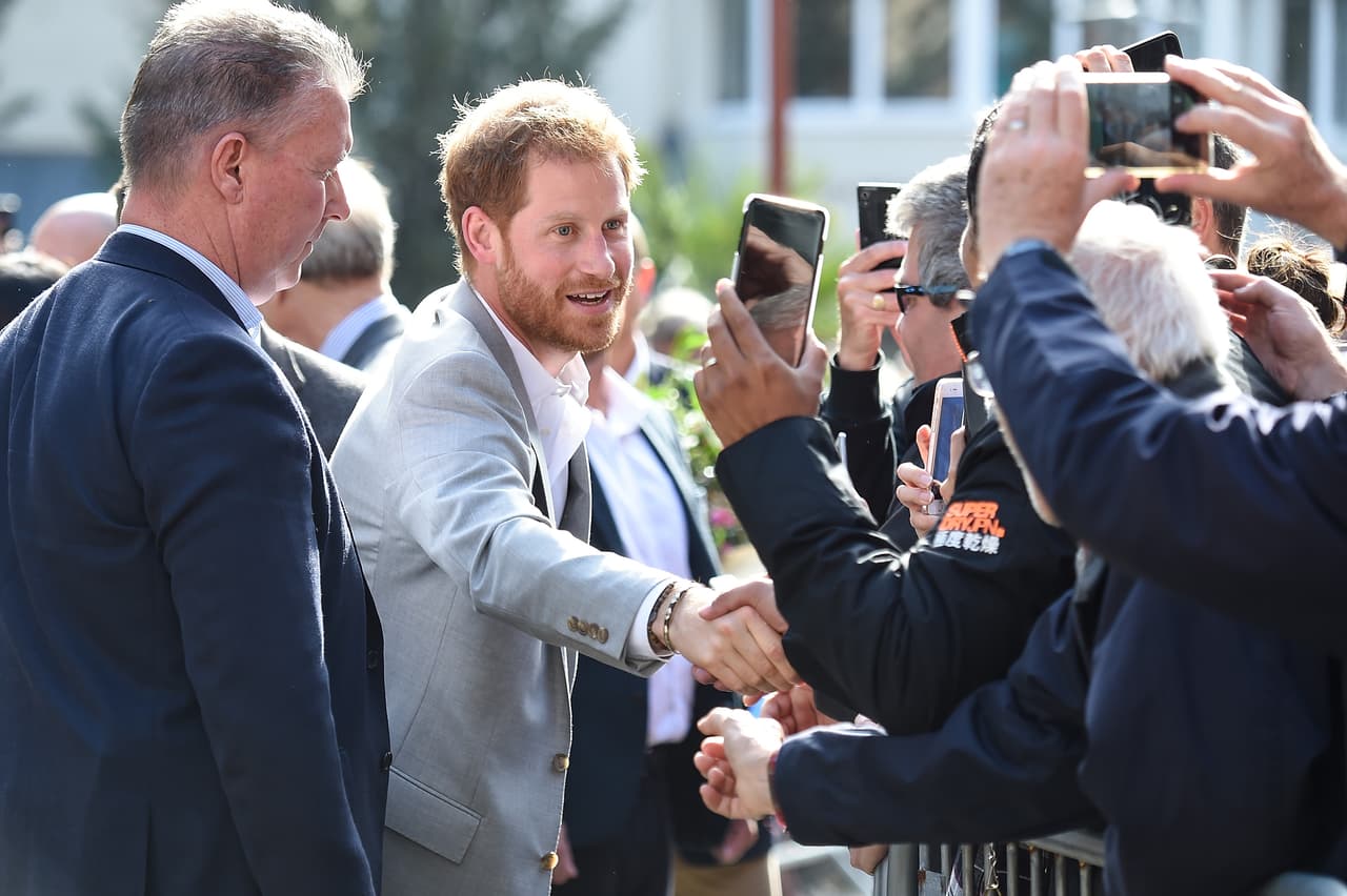 En modo 'multitasking': el príncipe Harry saludó a unos cuantos mientras posaba para los distintos celulares de quienes buscaban tener la mejor imagen suya.