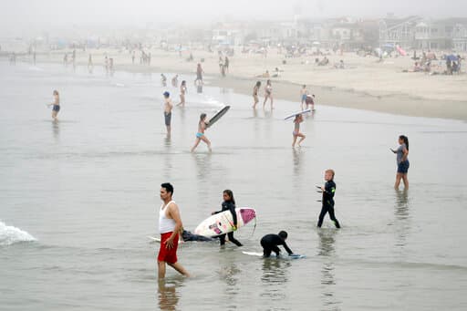 Nadadores y surfistas en la playa de Newport, California, este domingo.