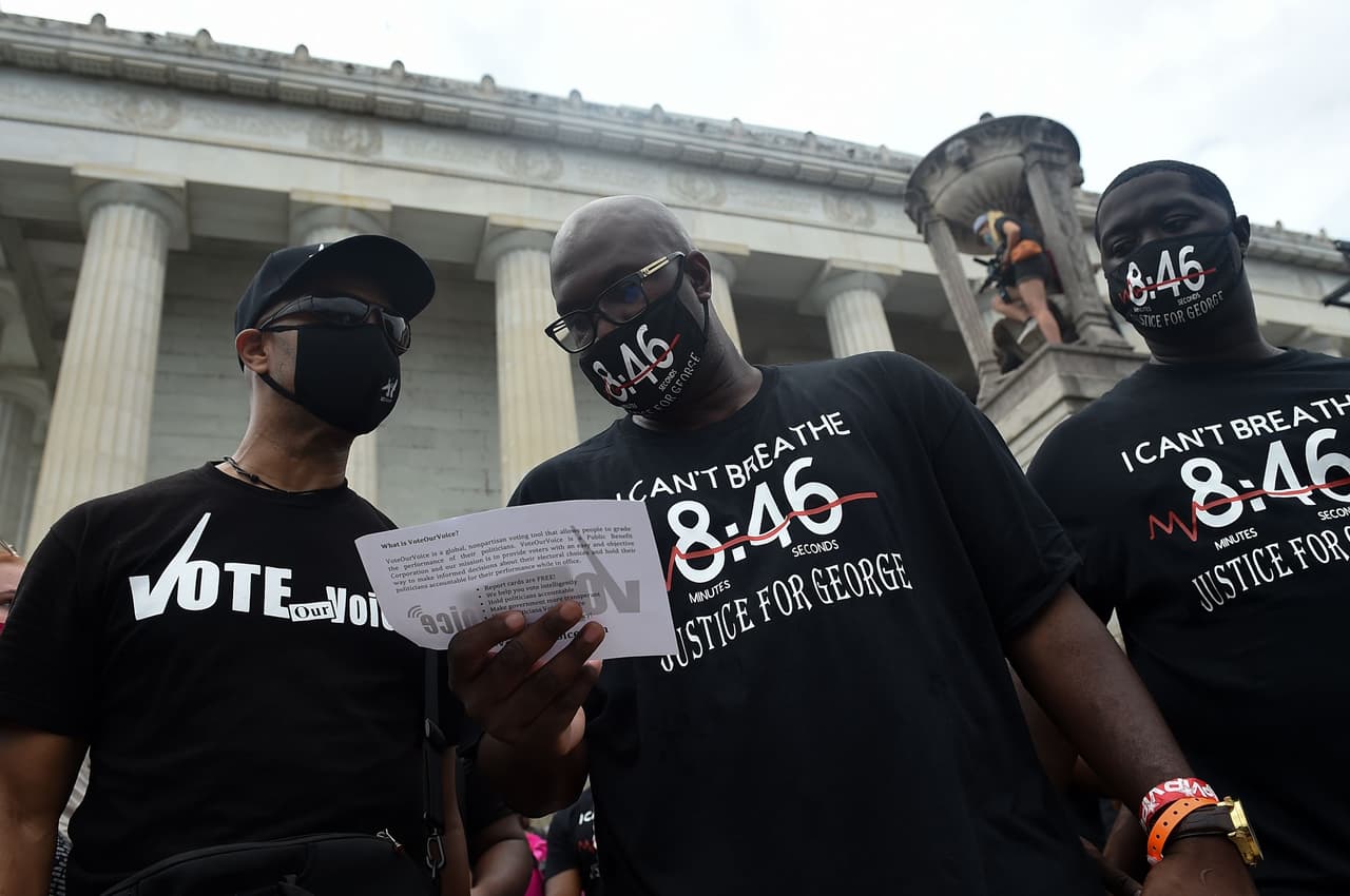 Philonise Floyd, hermano de George Floyd (al centro), lee un documento sobre el derecho al voto que fue distribuido a los asistentes.