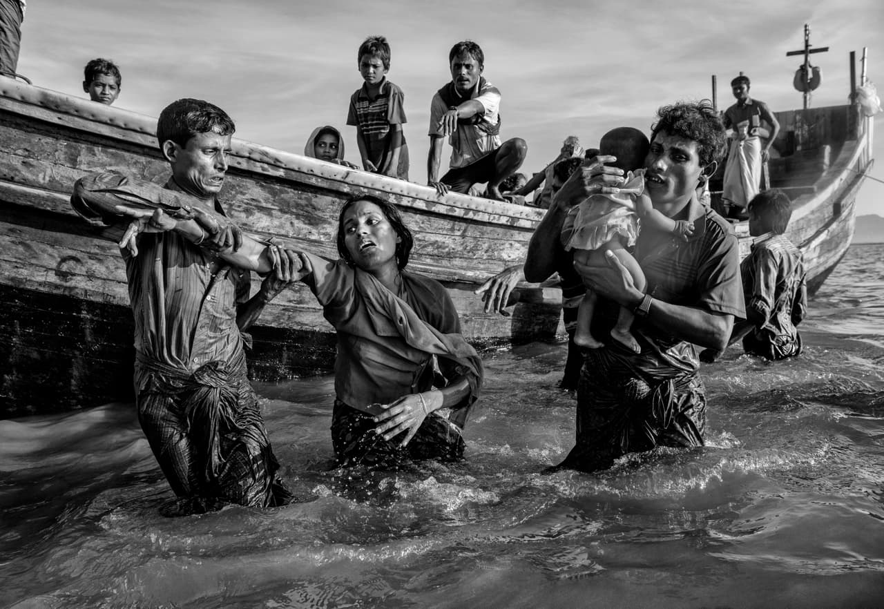 Una mujer refugiada rohingya es ayudada desde un bote cuando llega agotada en el lado de Bangladesh del río Naf. Tras meses de violencia, el pasado 25 de agosto estalló la actual crisis cuando insurgentes rohingyas volvieron a atacar en Rakhine puestos de policía y una base militar. Las fuerzas de seguridad de Myanmar reprimieron nuevamente.
