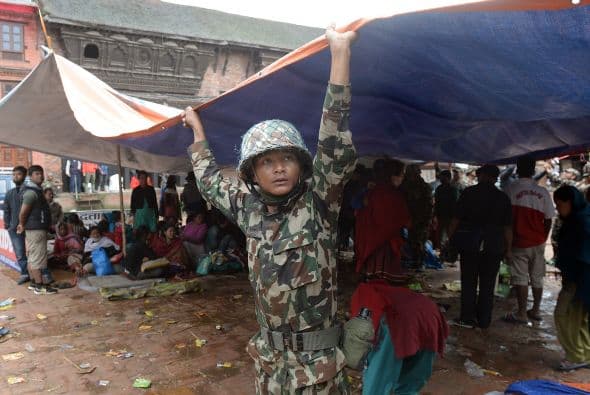 Un miembro de las fuerzas de seguridad ayuda a establecer casas de campaña.