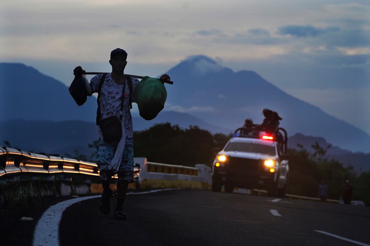 Un migrante camina por la carretera, seguido por un vehículo de la Guardia Nacional mexicana, hacia la salida a Huixtla, estado de Chiapas, México, al amanecer del jueves 9 de junio de 2022.
