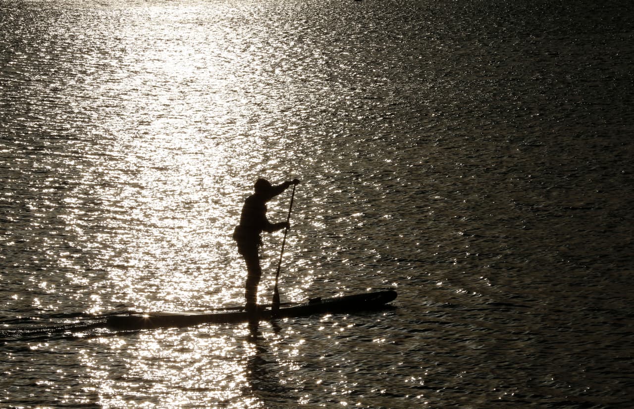 A man paddles a board across the Daiba Bay in Tokyo, Thursday, Dec. 14, 2017. (AP Photo/Shizuo Kambayashi)