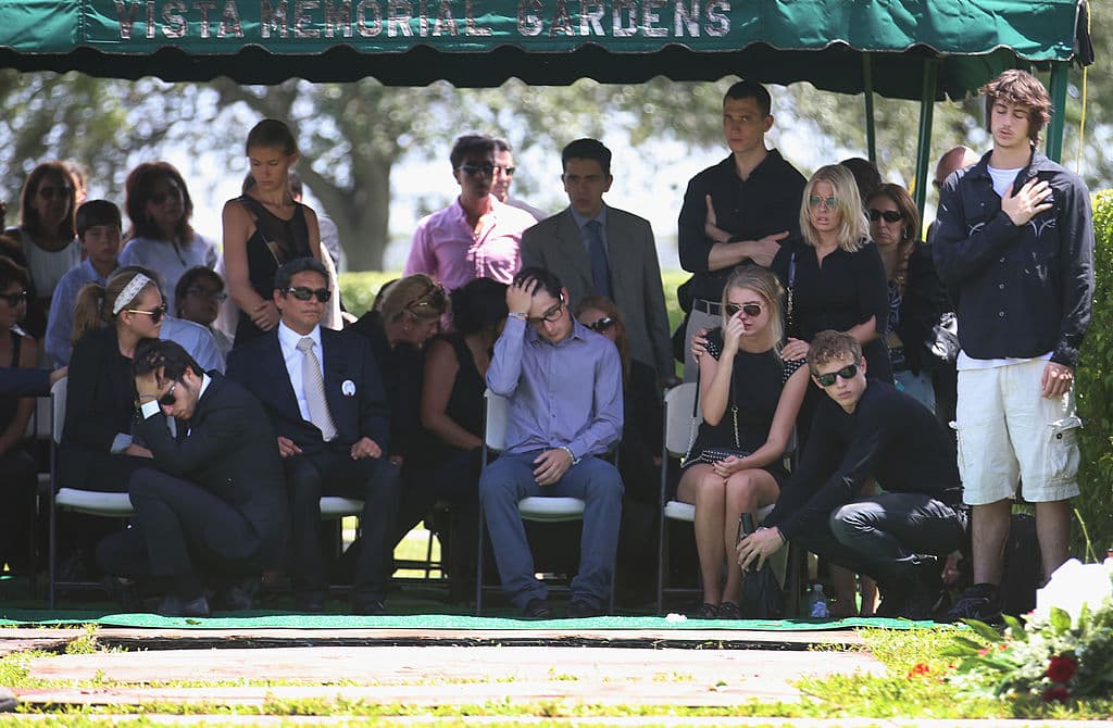 Family and friends sit near the burial plot after the internment of 18-year-old graffiti artist Israel Hernandez-Llach at the Vista Memorial Gardens & Funeral Home on Aug 14, 2013, a week after he died when he was Tasered by a Miami Beach police officer.