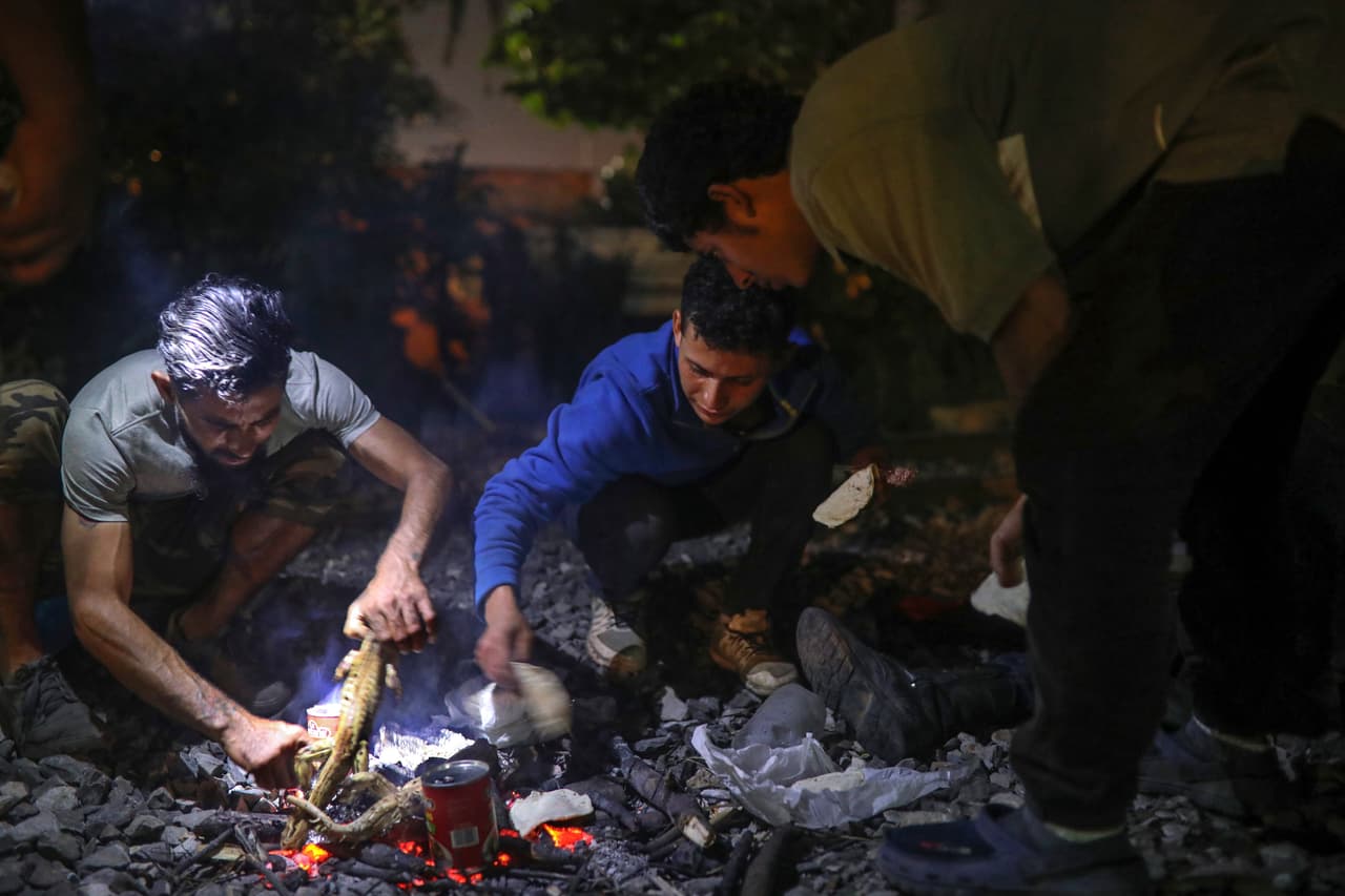 En esta foto del 21 de noviembre de 2019, migrantes centroamericanos cocinan iguanas que cazaron con resorteras junto a las vías del tren que esperan los lleve hacia el norte. La imagen fue tomada en Coatzacoalcos, en el estado mexicano de Veracruz. (AP Foto/Félix Márquez)