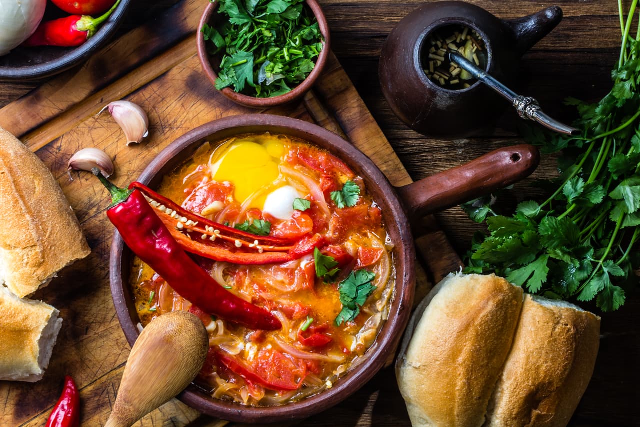Chilean food. "Picante Caliente" or "spicy hot" with onion, tomatos, chilli aand eggs in tipicacal chilleann cllay pan