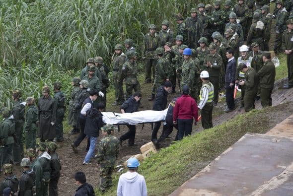 Los equipos de rescate cargan a una de las víctimas mortales del avión que cayó a un río en Taiwán.