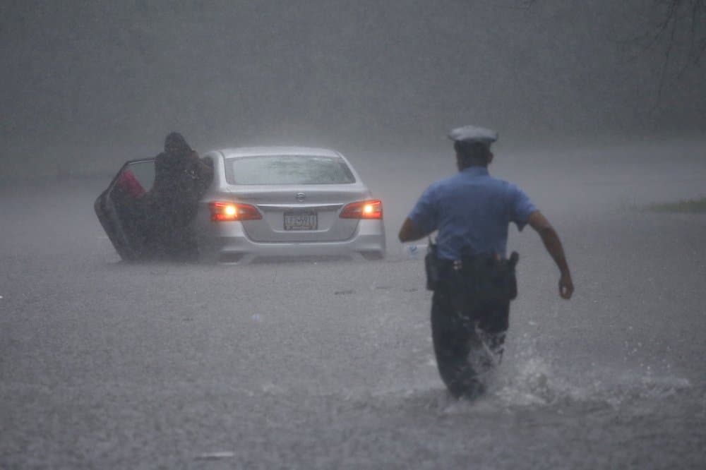 Un oficial de policía de Philadelphia corre a ayudar a un conductor cuyo vehículo quedó varado en medio de una calle inundada por las lluvias que arrojó la tormenta Isaías.