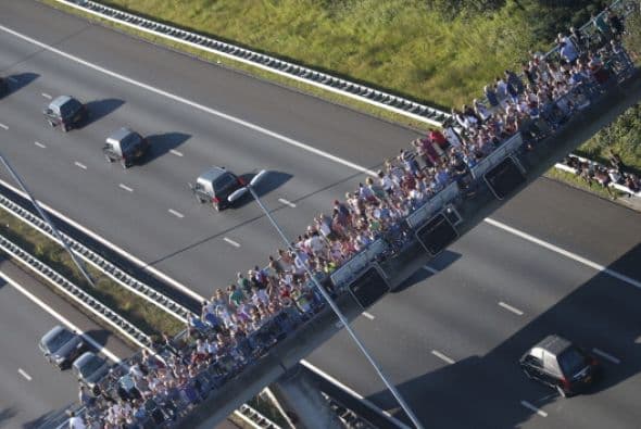 Esta foto aérea muestra a decenas de personas mirando pasar a un convoy de coches fúnebres que llevan los ataúdes con las víctimas.  