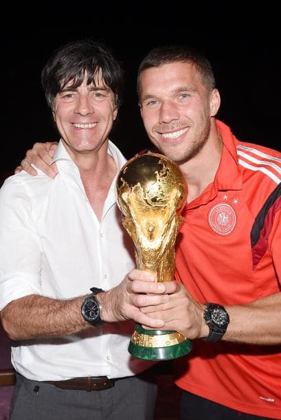 El técnico Joachim Löw junto a Lukas Podolski con el trofeo.