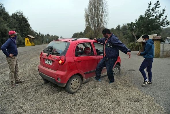 En los pies de estas personas y las llantas del vehículo se puede apreciar la cantidad de ceniza volcánica que quedó sobre la localidad.