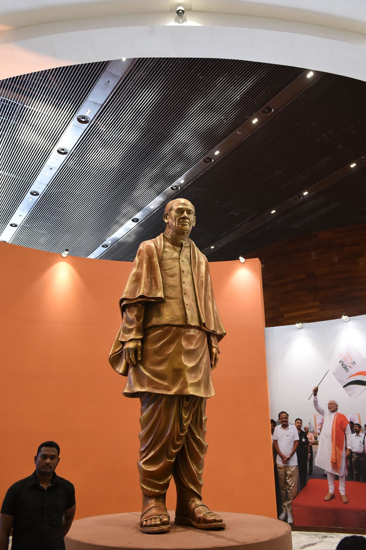 Un empleado del museo,
<br>
<br>An Indian museum staff (L) stands near a statue of Sardar Vallabhbhai Patel at a museum inside the "Statue Of Unity", the world's tallest statue dedicated to Indian independence leader Sardar Vallabhbhai Patel, near Vadodara in India's western Gujarat state on October 31, 2018. - India on October 31 inaugurated the world's biggest statue with pomp, fireworks and tight security amid an outcry among local groups over the cost of the 182 metre (600 feet) high reproduction of an Indian independence hero. (Photo by SAM PANTHAKY / AFP) (Photo credit should read SAM PANTHAKY/AFP/Getty Images)