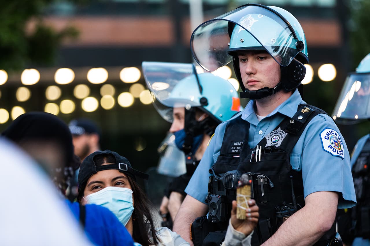 Un manifestante quema salvia mientras un oficial de policía mira hacia adelante durante las protestas contra la brutalidad policial y el racimo en Chicago.