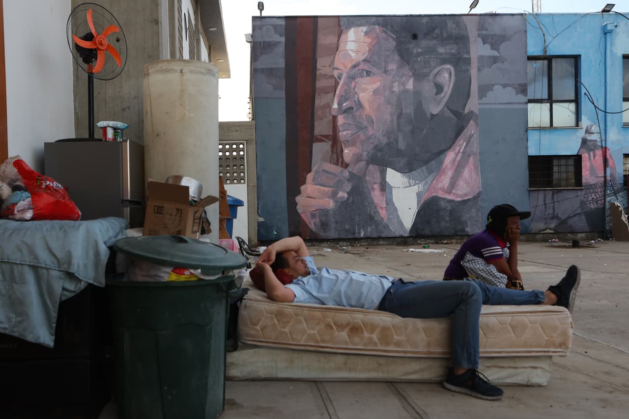 Un hombre de La Guaira duerme en la calle con la imagen de Hugo Chávez al fondo.
