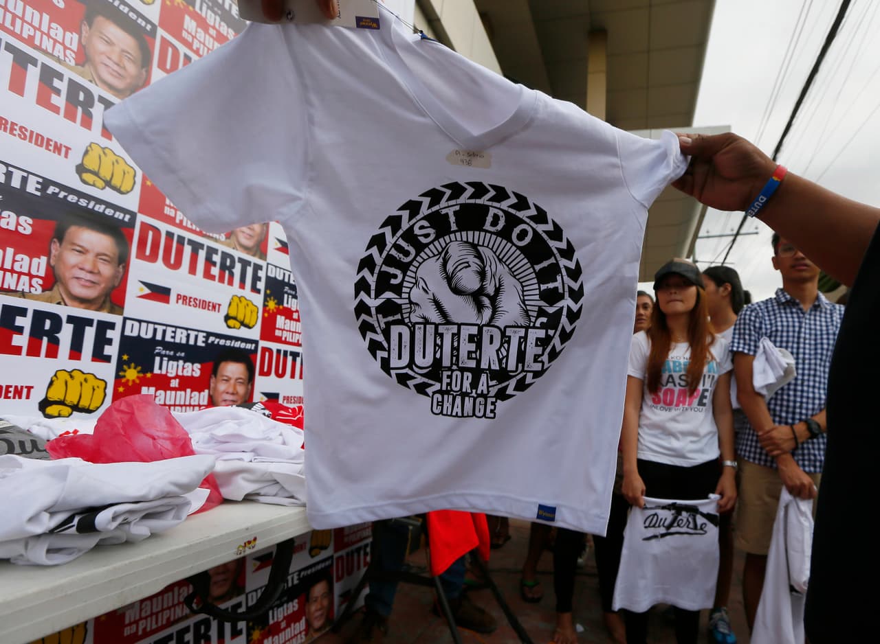 Unas personas observan una camiseta que promociona al candidato presidencial Rodrigo Duterte, en Davao, su ciudad natal, en Filipinas, el 8 de mayo de 2016. Millones de filipinos acudirán a las urnas para elegir presidente el 9 de mayo. (Foto AP/Bullit Marquez)