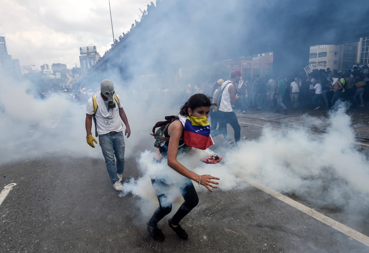 A female protester grab a tear gas canister in her gloved hand. April 6, 2017.