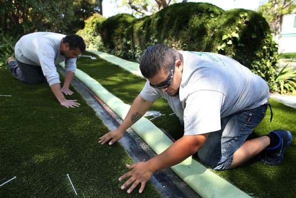 Debido a la dramática situación que viven en California, numerosos propietarios han optado por poner césped artificial, como medida para ahorrar agua. En la imagen, dos trabajadores lo instalan en una casa en Burlingame a principios de abril.