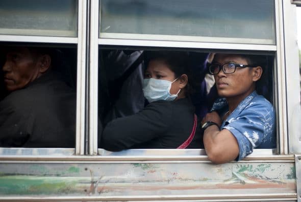 Trabajadores camboyanos miran por la ventana del autobús después de cruzar la frontera entre Tailandia.