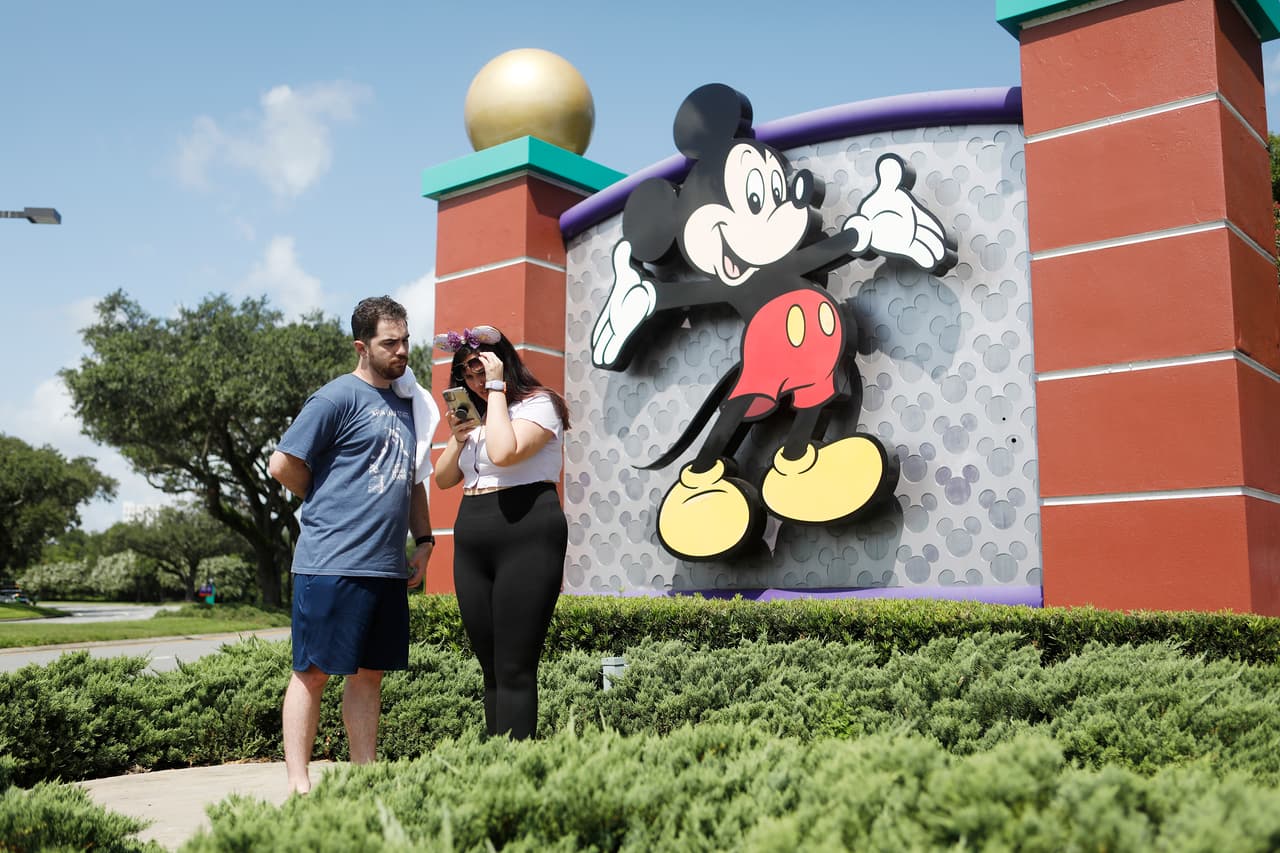 Turistas cerca de la entrada de Walt Disney World, este 9 de julio. Entre las medidas de seguridad informadas por la compañía, los niños mayores de 2 años y adultos deben llevar cubiertas faciales, tapabocas o mascarillas, en todas las áreas públicas. Los tradicionales personajes de Disney que pasean y saludan a los turistas en el parque no podrán ser abrazados ni tocados.